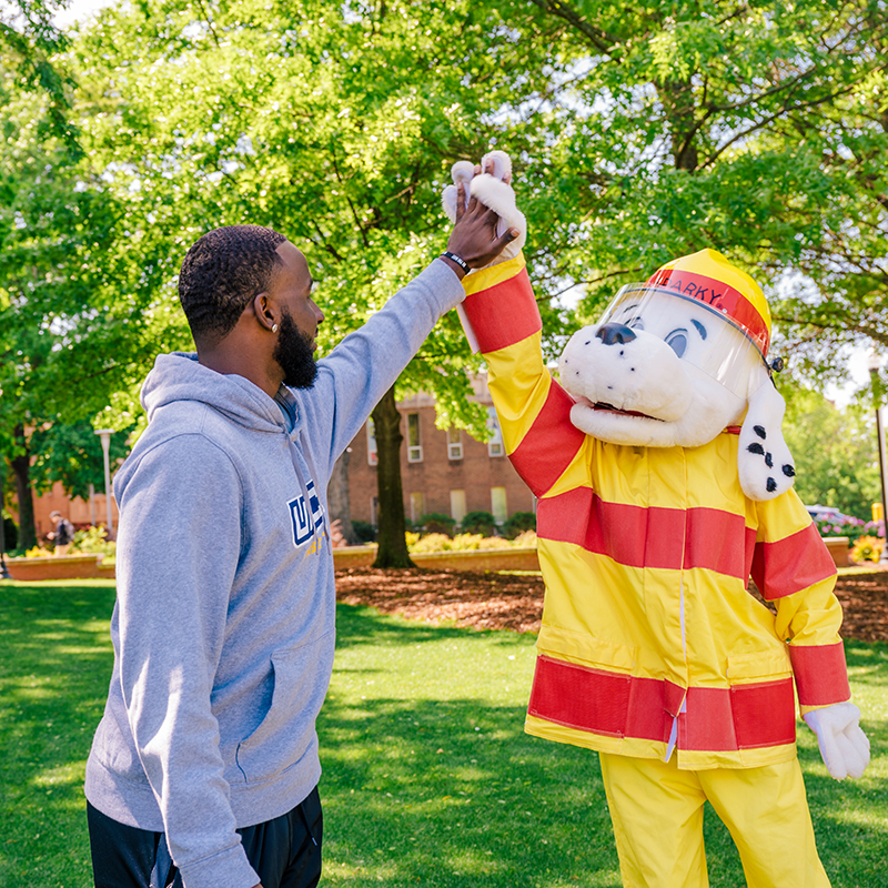 Student gives high five to Sparky the dog mascot